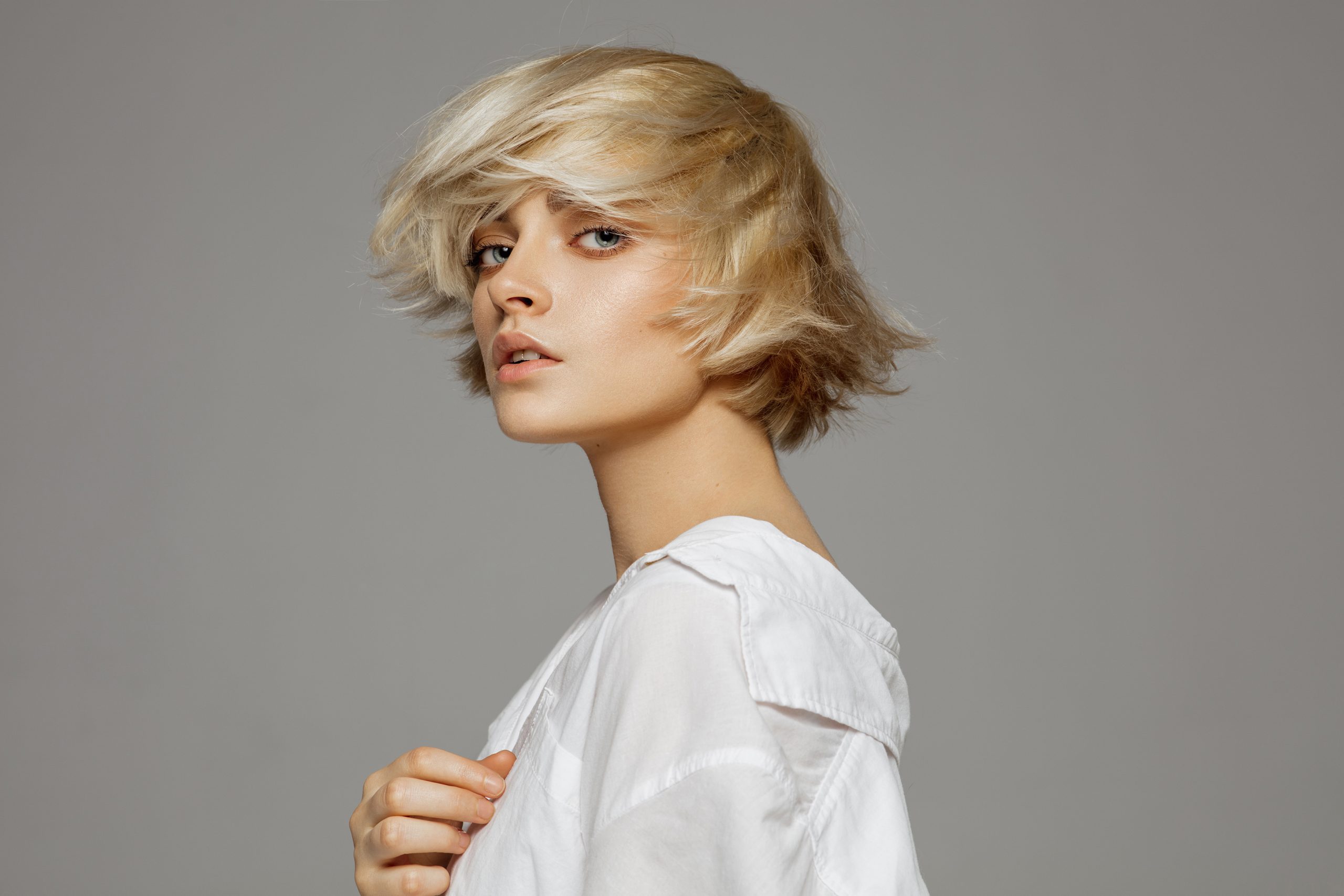 Portrait of beautiful blonde woman in white shirt and fashionable hair