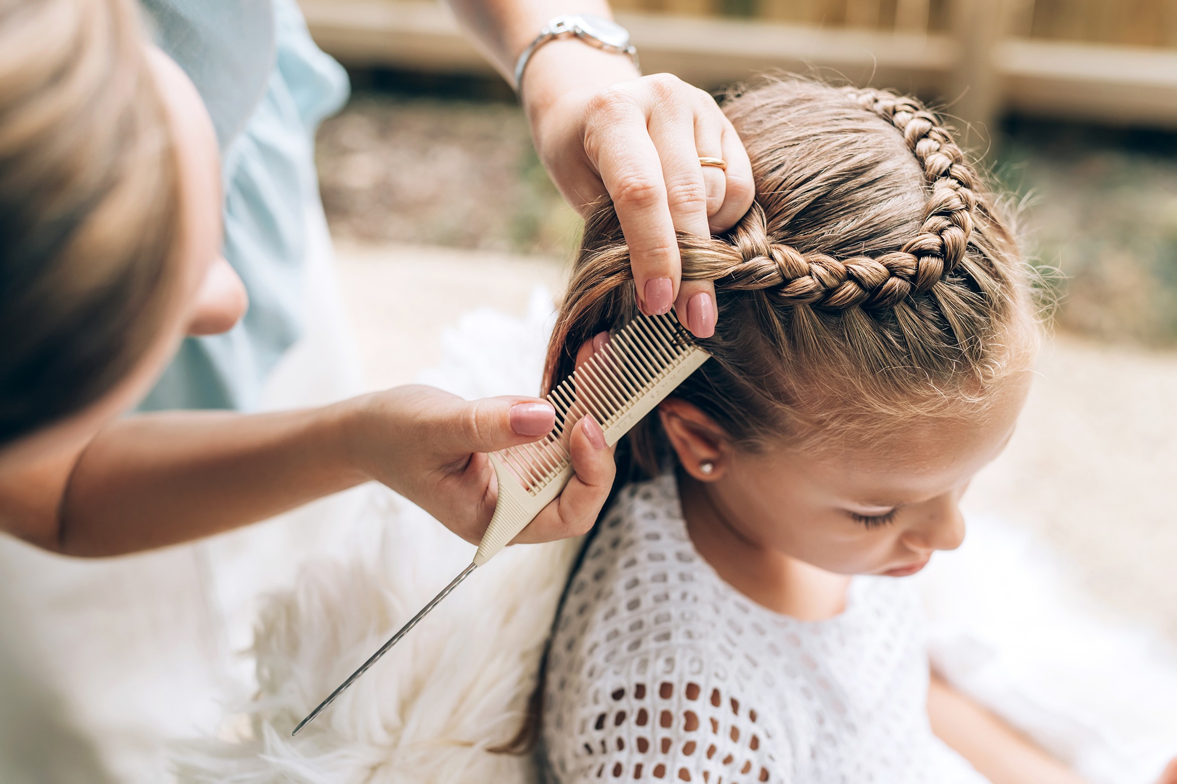 Mother does hair braid to her daughter, close up photo.