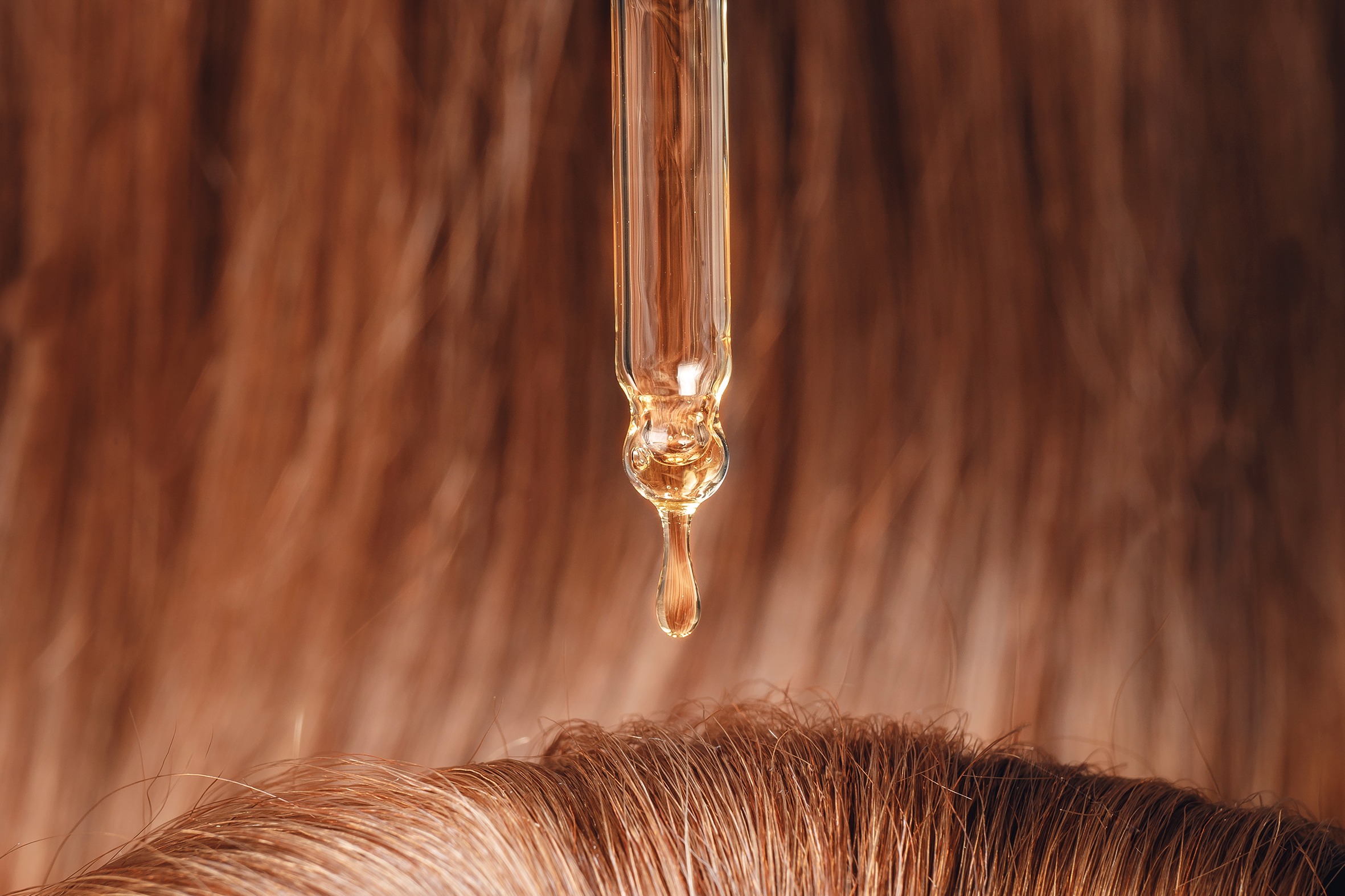 Close-up drop of oil restore and recovery hair is applied to head bulbs. Concept hairdresser spa salon.