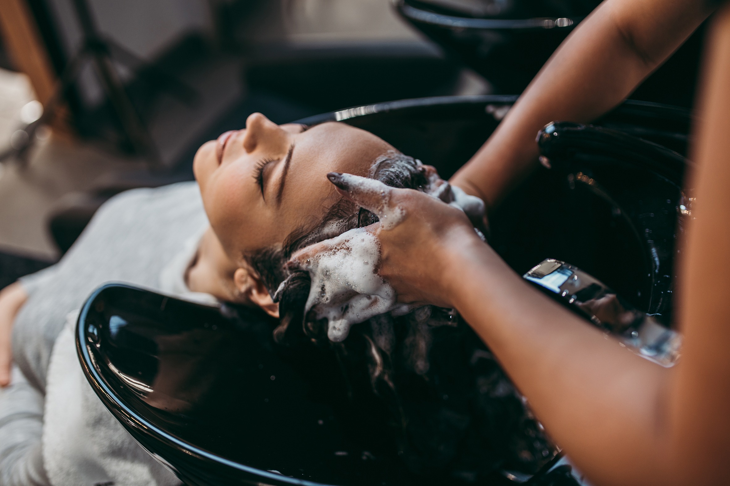 Beautiful young woman getting a hair wash. Hair salon styling concept.